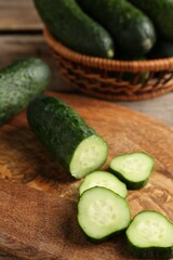 Cut and whole cucumbers on wooden table, closeup