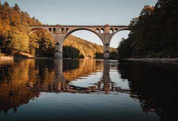 Fototapeta premium Autumnal Stone Bridge Over River Reflecting Sunset