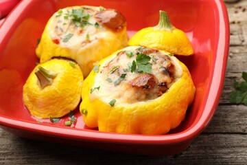 Tasty stuffed pattypan squashes in baking dish on wooden table, closeup