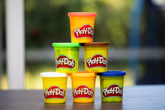 Six Stacked Play-doh compound modeling clay plastic containers in white, orange, pink, green, brown, blue in a pyramid 