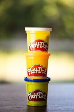 Three stacked Play-doh compound modeling clay containers in white, orange, and blue colors
