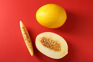 Whole and cut ripe melons on red background, flat lay