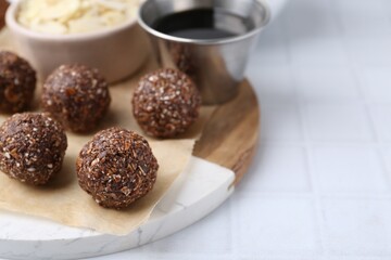 Making homemade candies. Chocolate balls and ingredients on white tiled table, closeup. Space for text