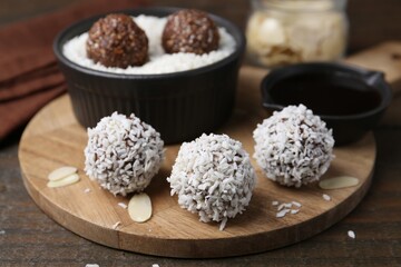 Delicious homemade candies with coconut flakes on wooden table, closeup