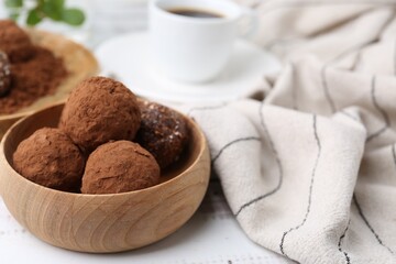 Delicious homemade candies with cocoa powder and coffee on white wooden table, closeup