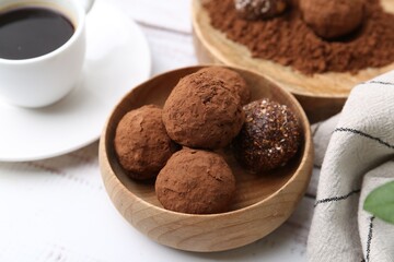 Delicious homemade candies with cocoa powder and coffee on white wooden table, closeup