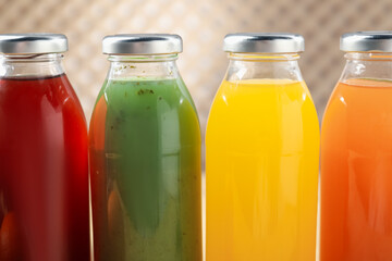 Tasty juices in glass bottles on blurred background, closeup