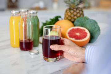 Woman with glass of tasty juice at white marble table indoors, closeup