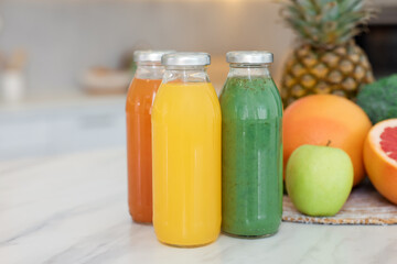 Tasty juices in glass bottles and fresh ingredients on white marble table indoors, closeup