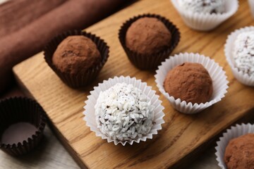 Delicious homemade candies with cocoa powder and coconut flakes on table, closeup