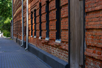 Red brick building facade in a quiet alleyway, showcasing classic architecture with wooden door and symmetrical windows. Ideal for themes of history, urban exploration, or architecture.
