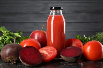 Tasty juice in glass bottle and ingredients on black marble table, closeup