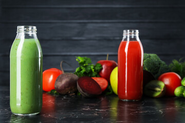 Tasty juices in glass bottles and ingredients on black marble table