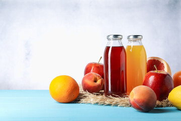 Tasty juices in glass bottles and fresh fruits on light blue wooden table, space for text