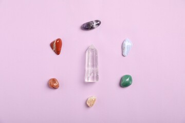 Seven chakra gemstones on lilac background, flat lay