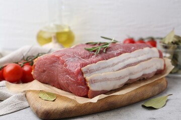 Piece of raw beef meat, tomatoes and spices on grey table, closeup