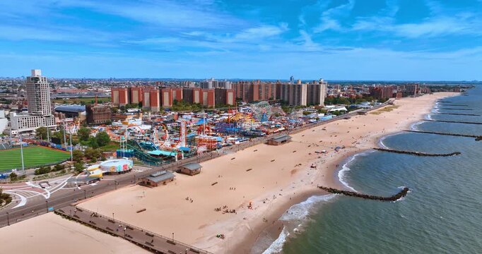 Approaching the sandy beach of Coney Island in Brooklyn. Aerial perspective on the amusement park with diverse attractions.