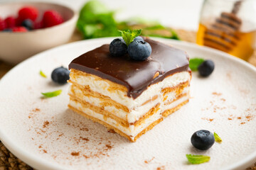 Layered cookie cake with cream and chocolate topping and fresh blueberries