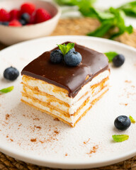 Layered cookie cake with cream and chocolate topping and fresh blueberries
