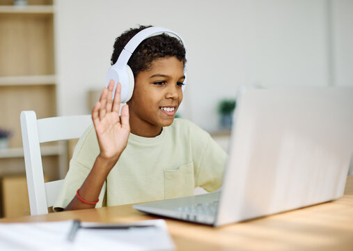 Portrait of a teenage boy  having fun using laptop wearing headphones and listening to the sound or music or doing homework and learning with laptop at home