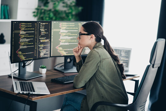 Professional female programmer working on a project using multiple computer monitors in a modern office setting
