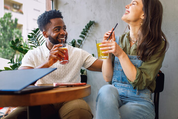 Happy young couple relaxing and talking while sitting together in cozy modern cafe.