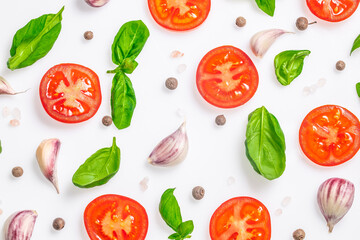 Fresh tomato slices with basil leaves, garlic cloves, and peppercorns on white background. top view