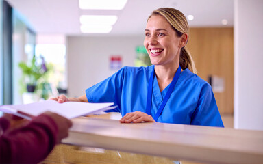 Nurse handing medical record to patient at hospital reception desk