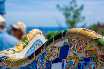 Detail of the curved bench by Gaudi in Parc Guell. Blurry tourists in the background.