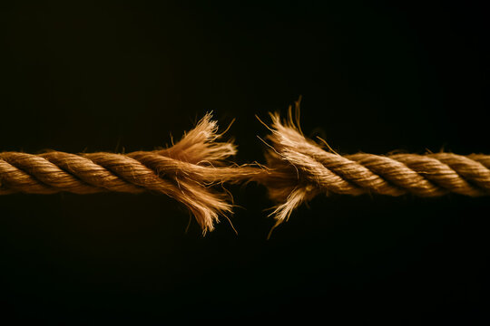 Close-up of frayed rope highlighting tension and separation