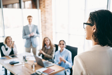 Business professional addressing team during collaborative office meeting focused on group motivation and project planning