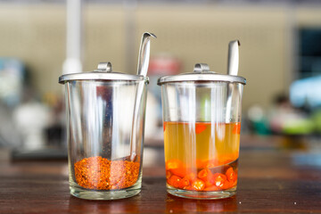 Chilli powder and spicy pickled sliced chili in vinegar. Seasoning for noodle on the table