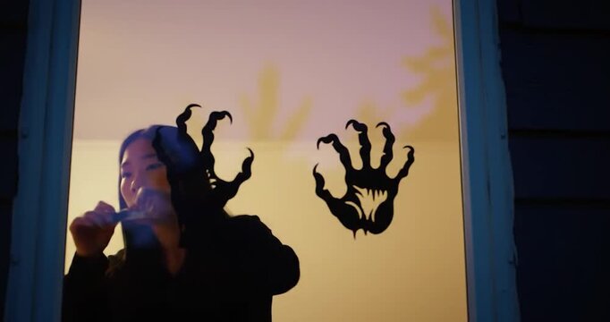 Spooky Halloween silhouette decoration being placed on a window at dusk