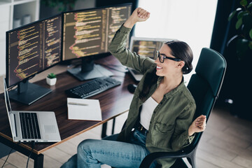 Enthusiastic female programmer celebrating success while working on codes in a modern workspace