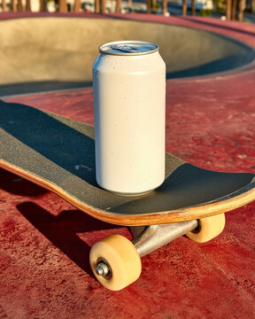 An aluminum soda can standing on a skateboard at a skate park. Refreshing summer drinks.