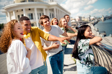 Group of happy young friends enjoying a summer day together at a scenic riverside location with urban views