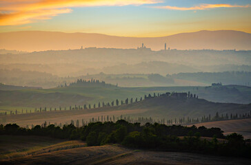 Siena appears on the top of rolling hills at sunset