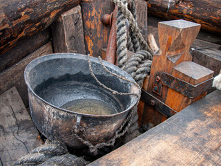 metal cauldron with ropes on wooden deck of traditional wooden ship, rustic maritime cooking...