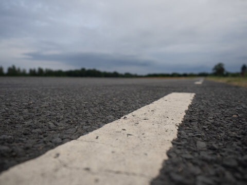 Close-up of asphalt road with white line, low angle view symbolizing travel, journey and transportation. - Powered by Adobe