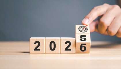 Hand placing a wooden block with number 5 to 6 change year 2025 to 2026 on a grey background.