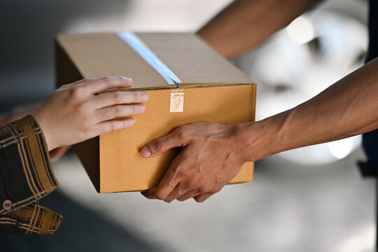Close-up shot of hands exchanging a cardboard box during a delivery, Home Delivery Concept