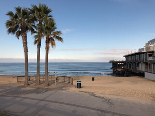 Beautiful isolated solitary ocean sandy beach surrounded by palm trees and rocks at Californian coast with Pacific surf on sunny day, retreat from hectic and stress exhale peace of mind