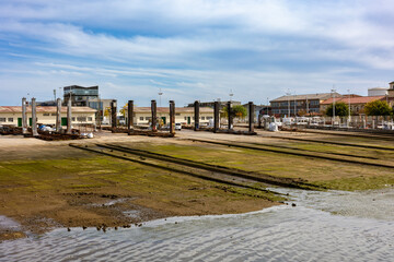 Fototapeta premium The Rampa del cuadro in the fishing harbor of Santander, Cantabria, Spain. Boat cradles on slipway tracks lead from the water edge up to a working boatyard with industrial buildings and metal pillars