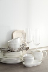 Different clean white dishware and glasses on counter in kitchen
