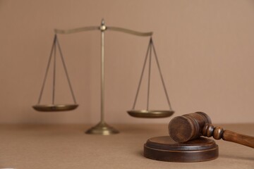 Golden scales of justice and gavel on light brown background, selective focus