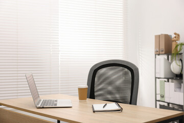 Stylish workplace with laptop, coffee and stationery on wooden table in office