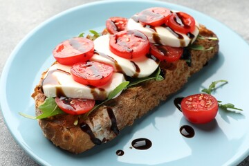 Delicious sandwich with mozzarella cheese, balsamic sauce, tomato and arugula on table, closeup