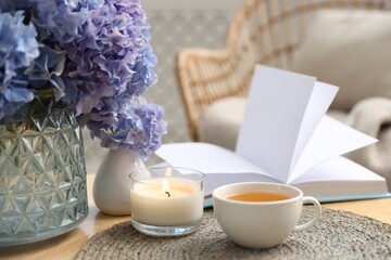 Spa composition with burning candle, beautiful hydrangea flowers, tea and book on table, closeup