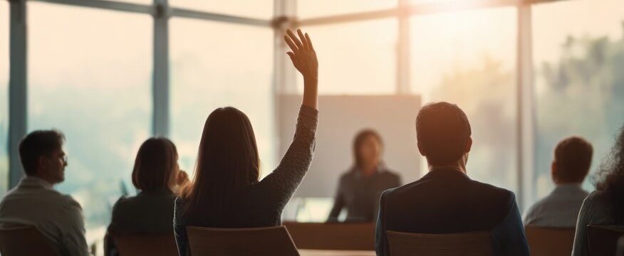 The engaged audience raises hands during a business presentation in a modern conference room.