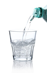 Pouring refreshing soda water from bottle into glass on white background